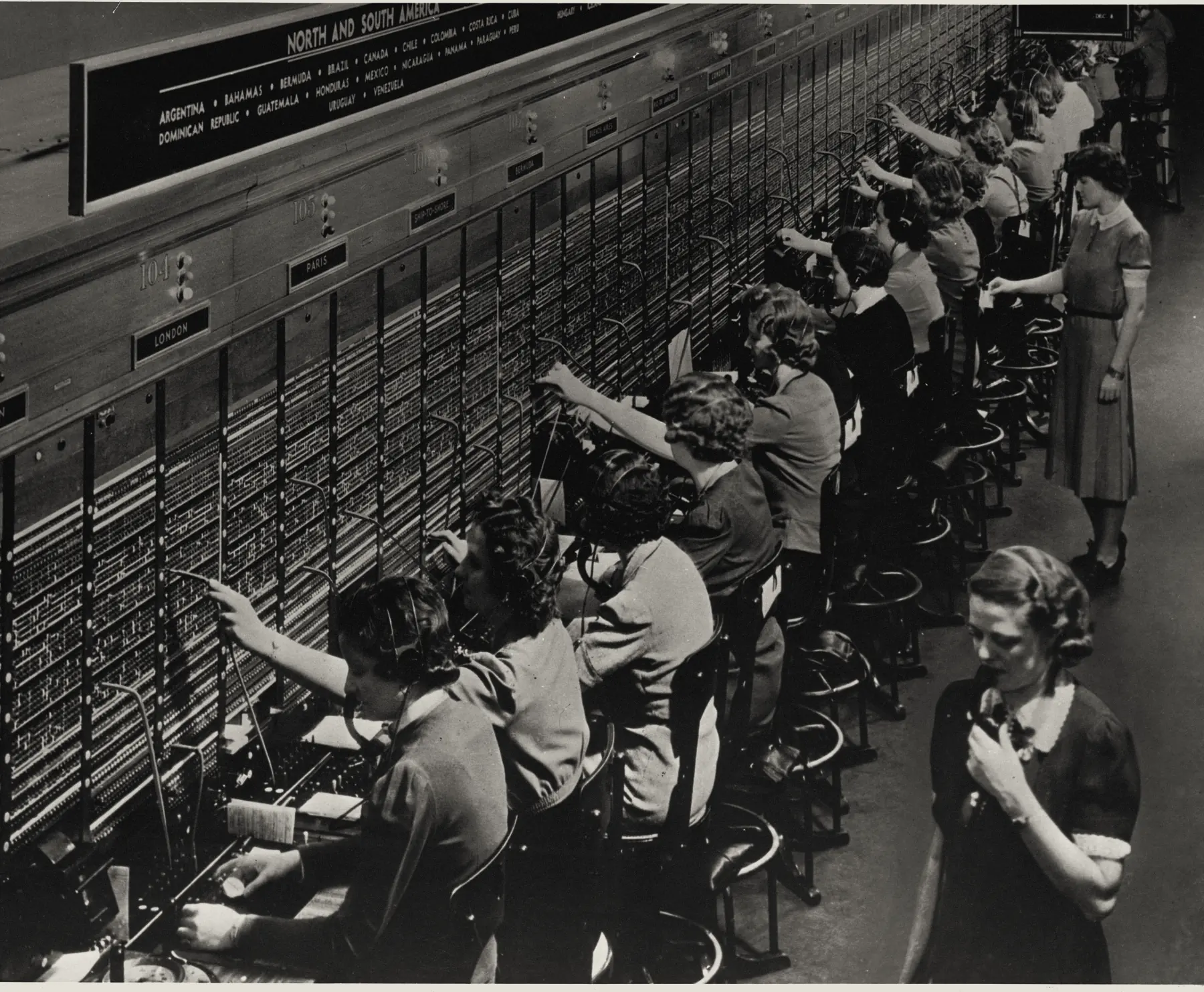 Operators connecting calls by hand at a Bell System international switchboard